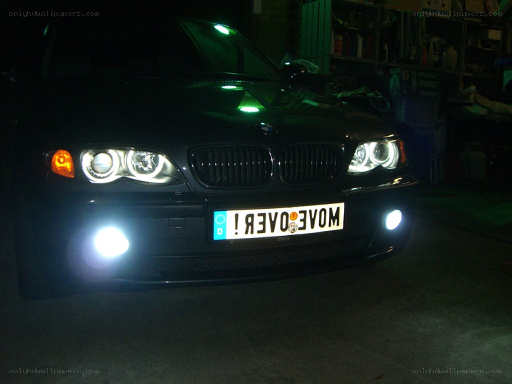 Black BMW with headlights on