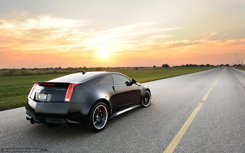 Black Cadillac on a road at sunset