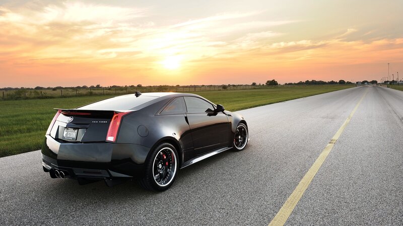 Black Cadillac on a road at sunset
