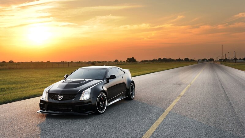 Black Cadillac on a road at sunset