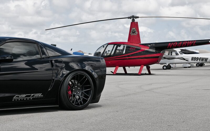 Black car and helicopter on tarmac