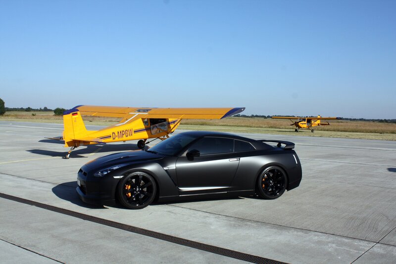Black car and yellow planes on tarmac