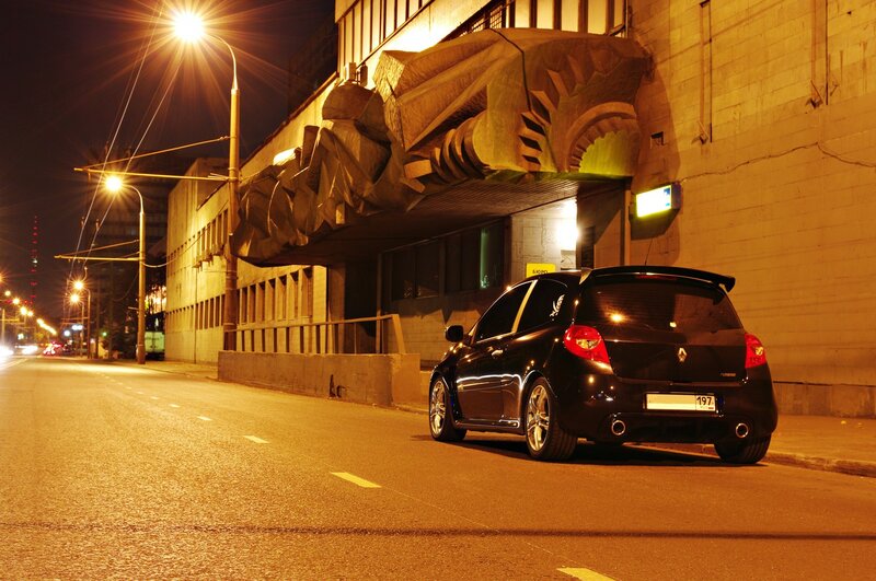 Black car at night near sculpture