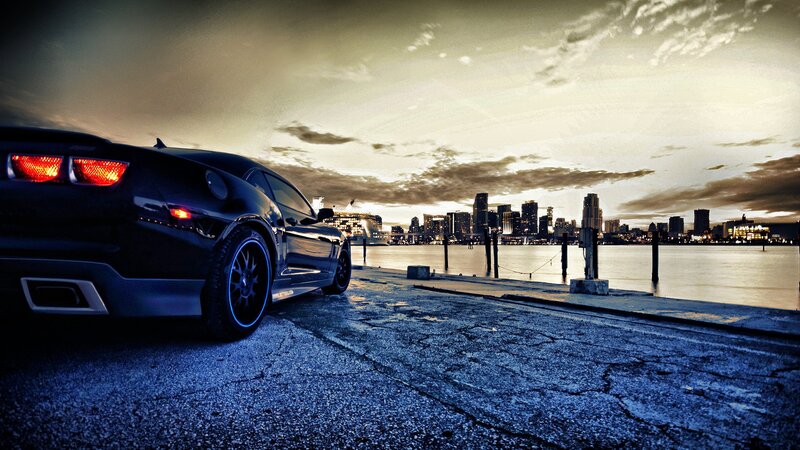 Black car at waterfront with city skyline