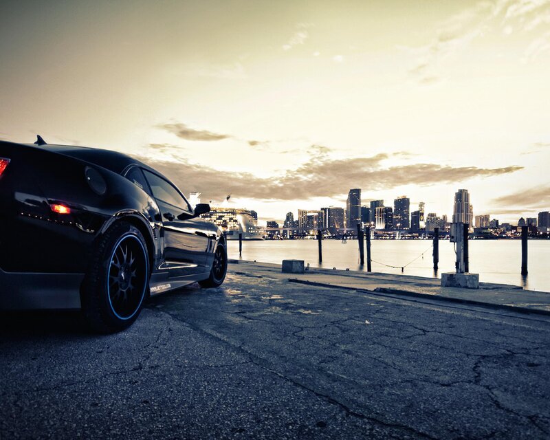 Black car at waterfront with city skyline