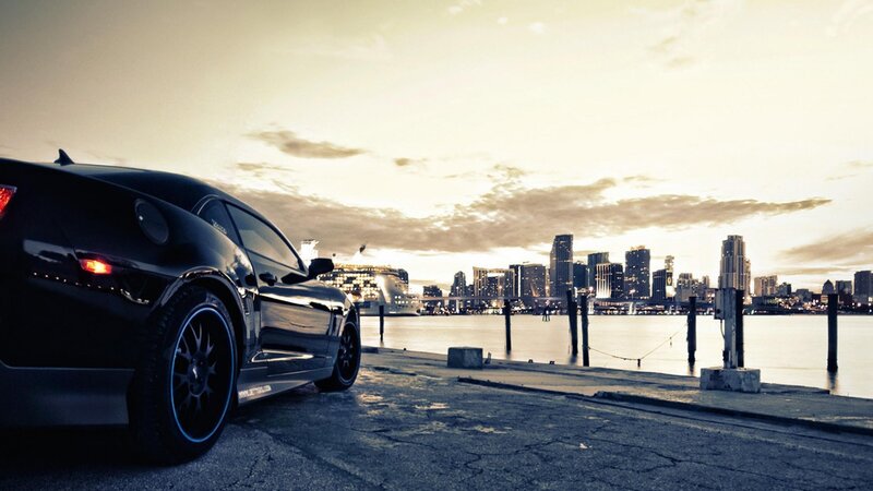 Black car at waterfront with city skyline