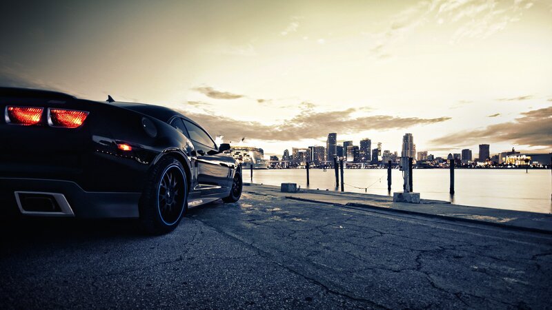 Black car at waterfront with city skyline
