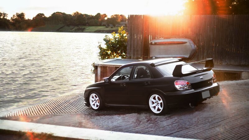 Black car by the lake at sunset