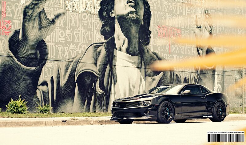 Black car in front of mural