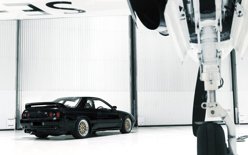 Black car in hangar with aircraft