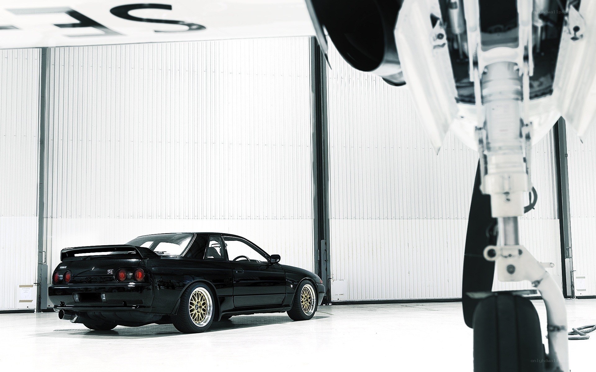 Black car in hangar with aircraft