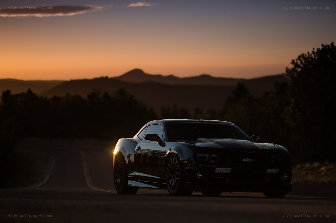 Black car on mountain road at sunset