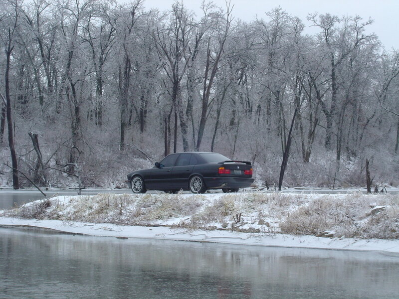 Black car on snowy riverbank