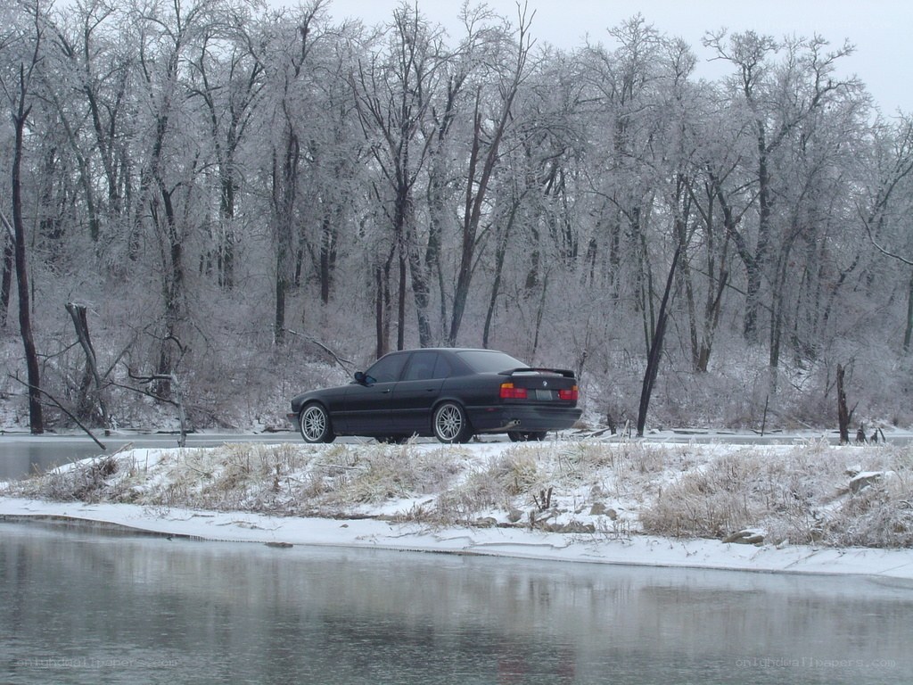 Black car on snowy riverbank