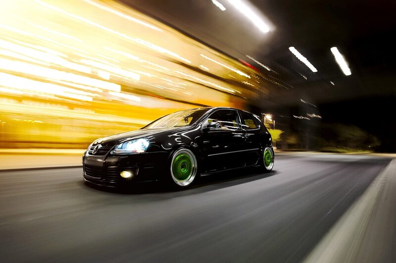 Black car with green wheels at night