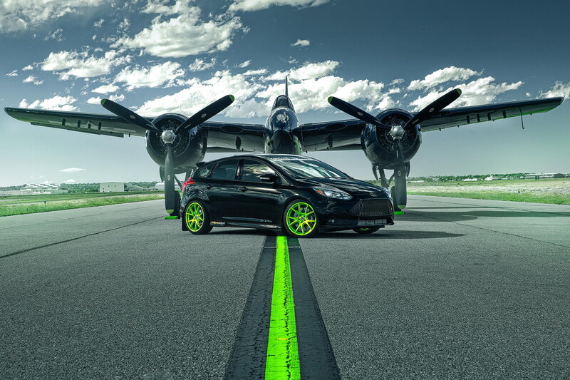 Black car with green wheels on runway