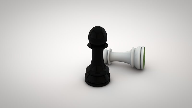 Black chess piece standing over fallen white pawn