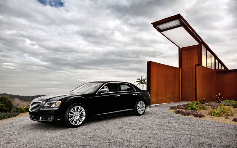 Black Chrysler 300 parked outside modern house