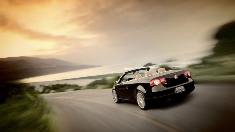 Black convertible driving on coastal road