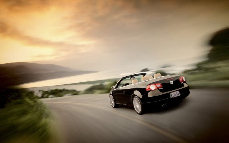 Black convertible driving on coastal road