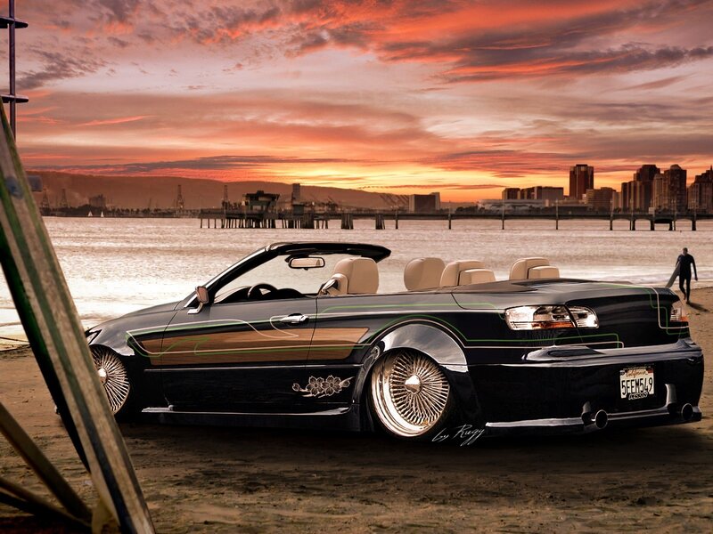 Black convertible on beach at sunset
