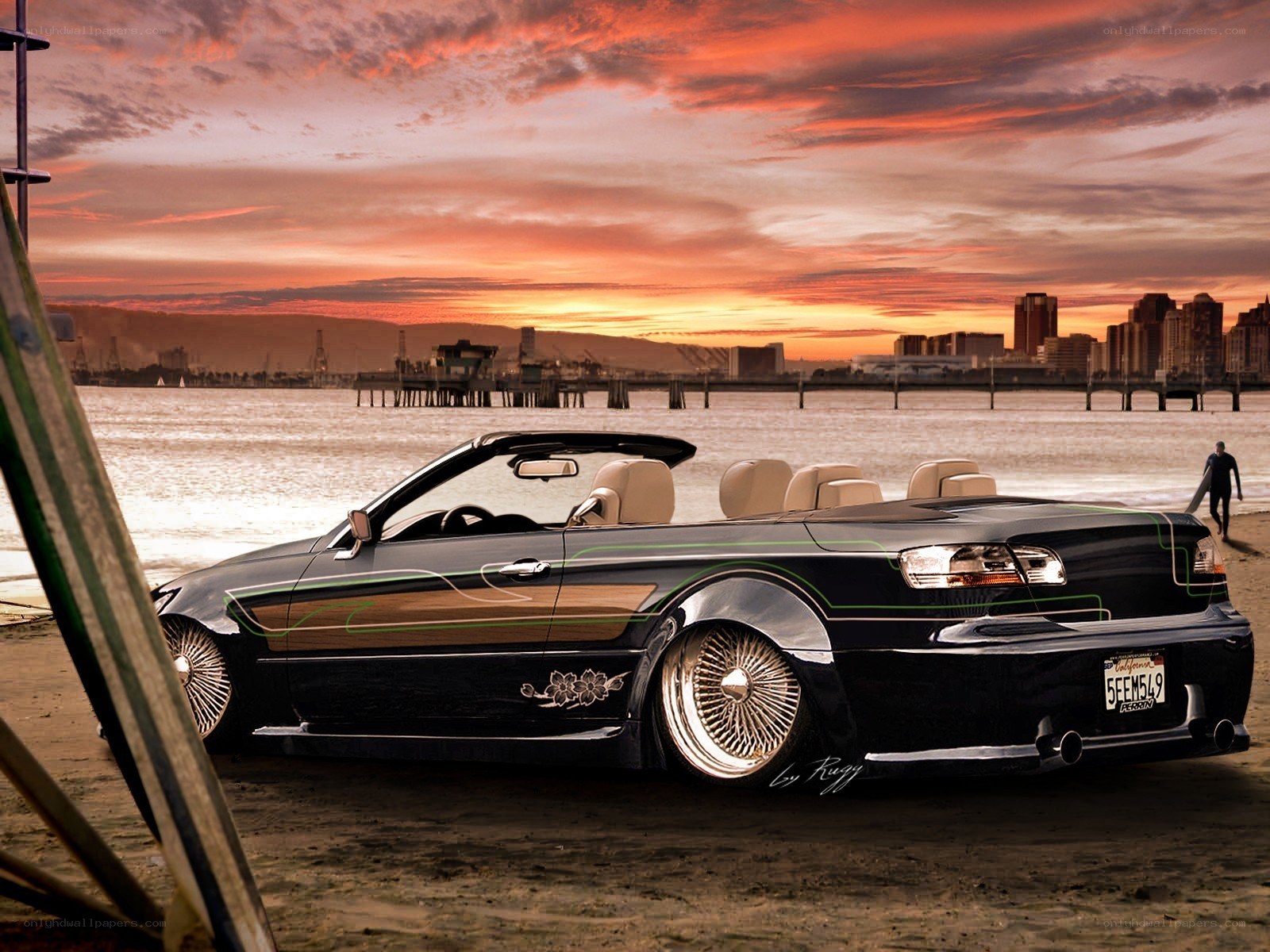 Black convertible on beach at sunset