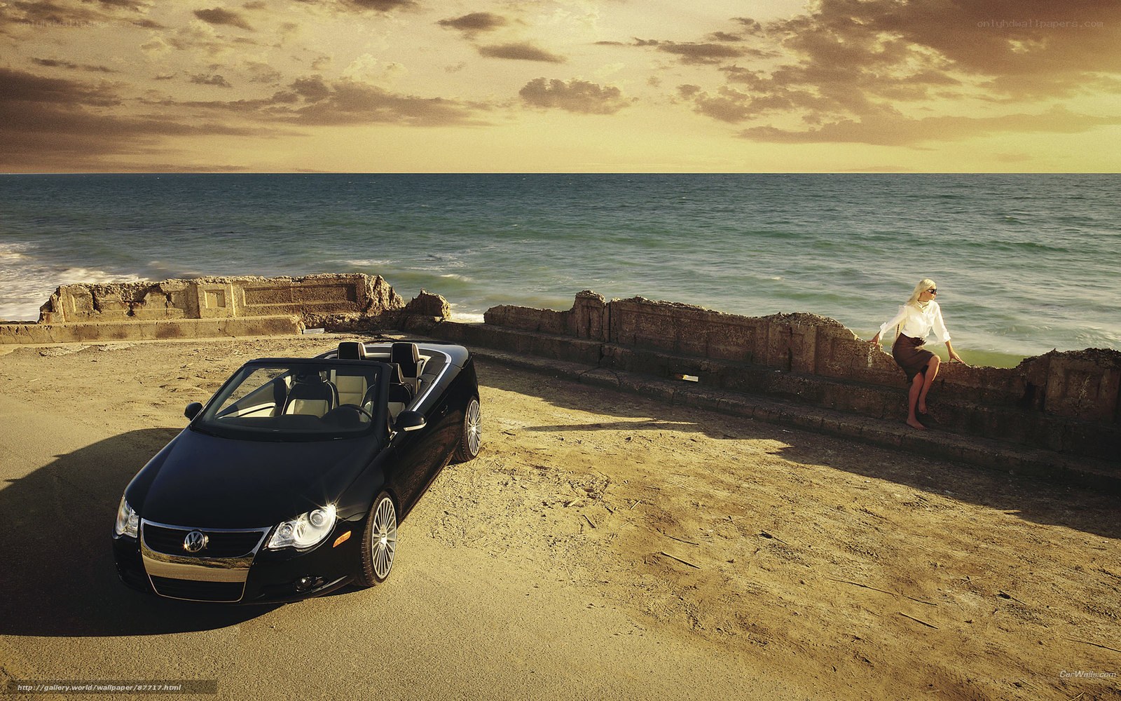 Black convertible on beach at sunset
