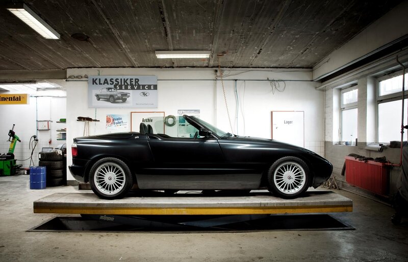Black convertible on lift in garage