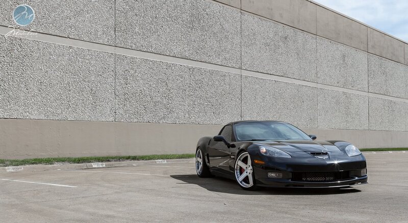 Black Corvette parked by wall