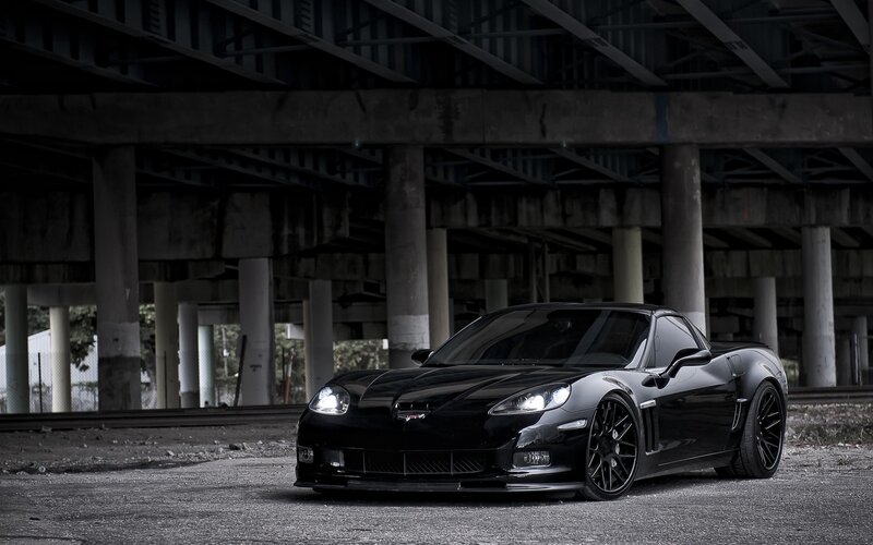 Black Corvette under a bridge