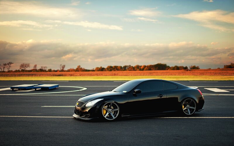 Black coupe on a tarmac at sunset
