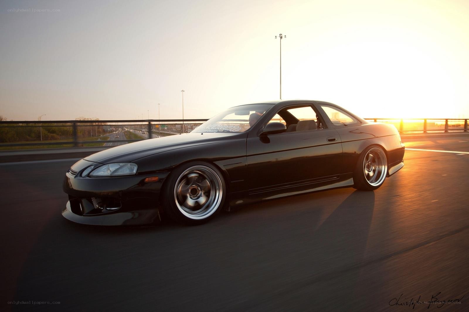 Black coupe on highway at sunset