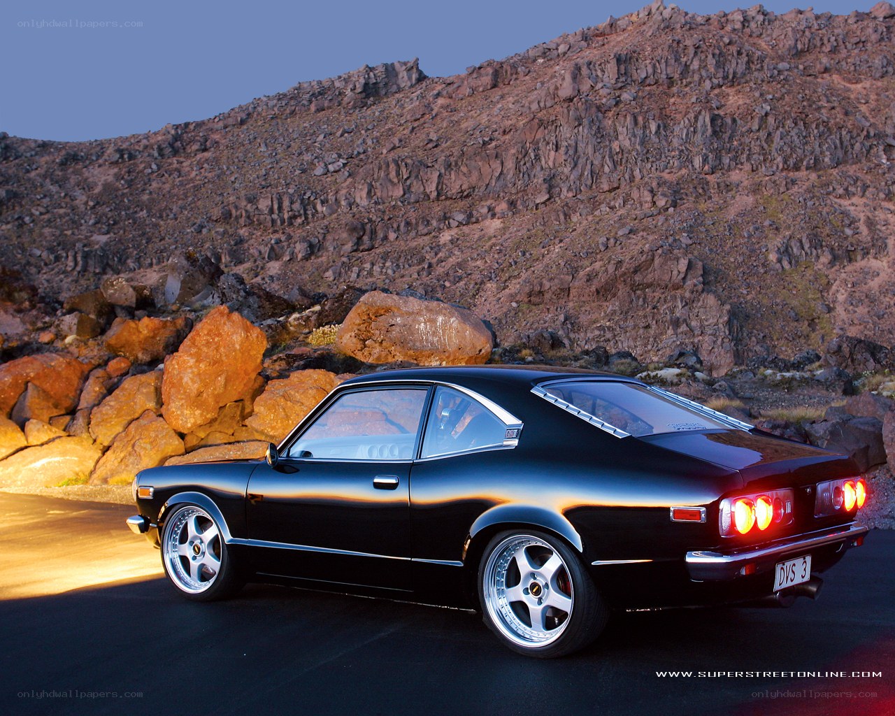 Black coupe on rocky road