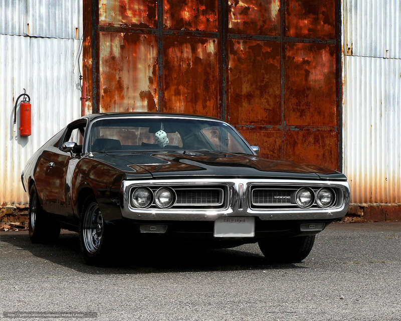 Black Dodge Charger in front of rusted wall