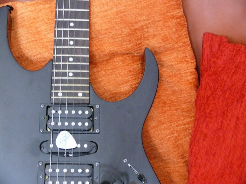 black electric guitar on orange fabric