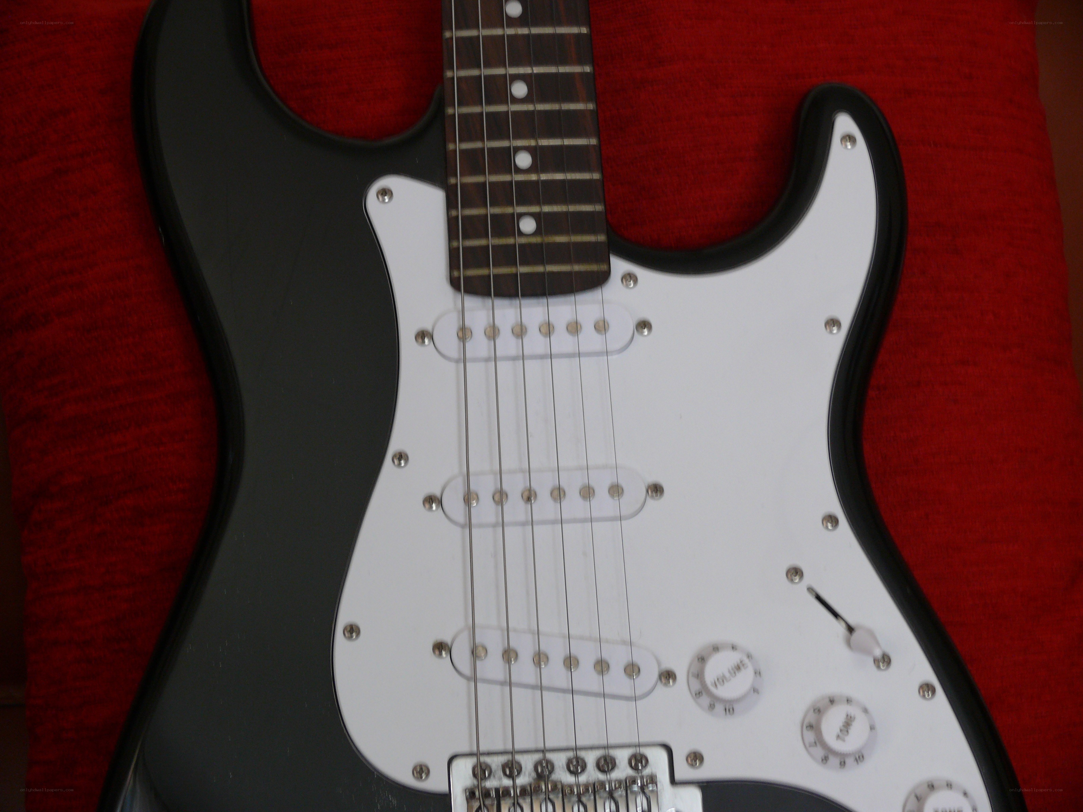 black electric guitar on red