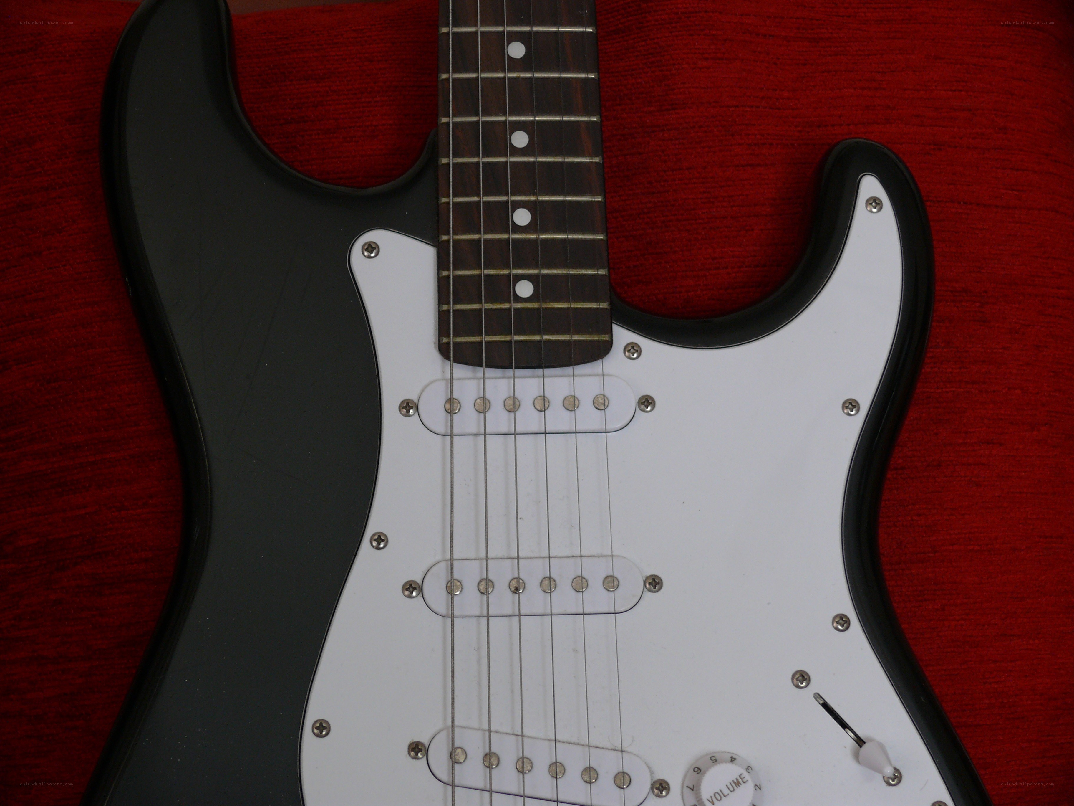 black electric guitar on red