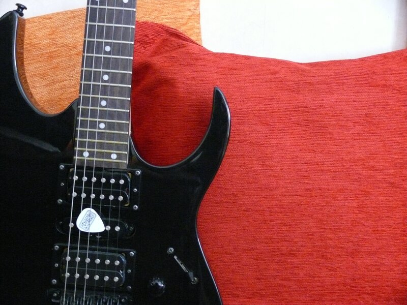 black electric guitar on red cushion
