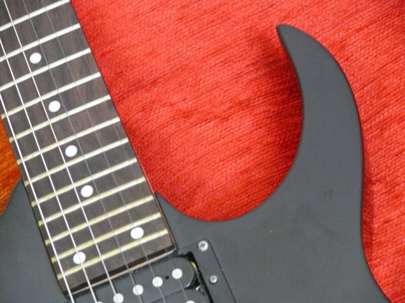 black electric guitar on red fabric