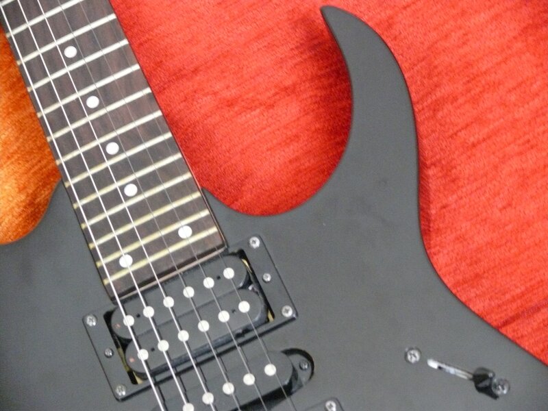black electric guitar on red fabric