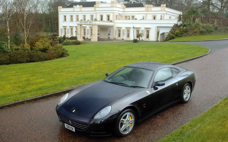 Black Ferrari in front of a mansion