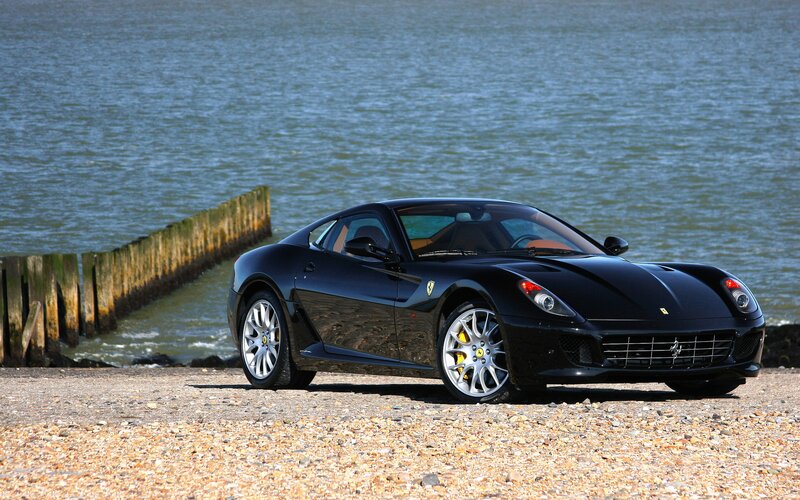 Black Ferrari sports car by the water