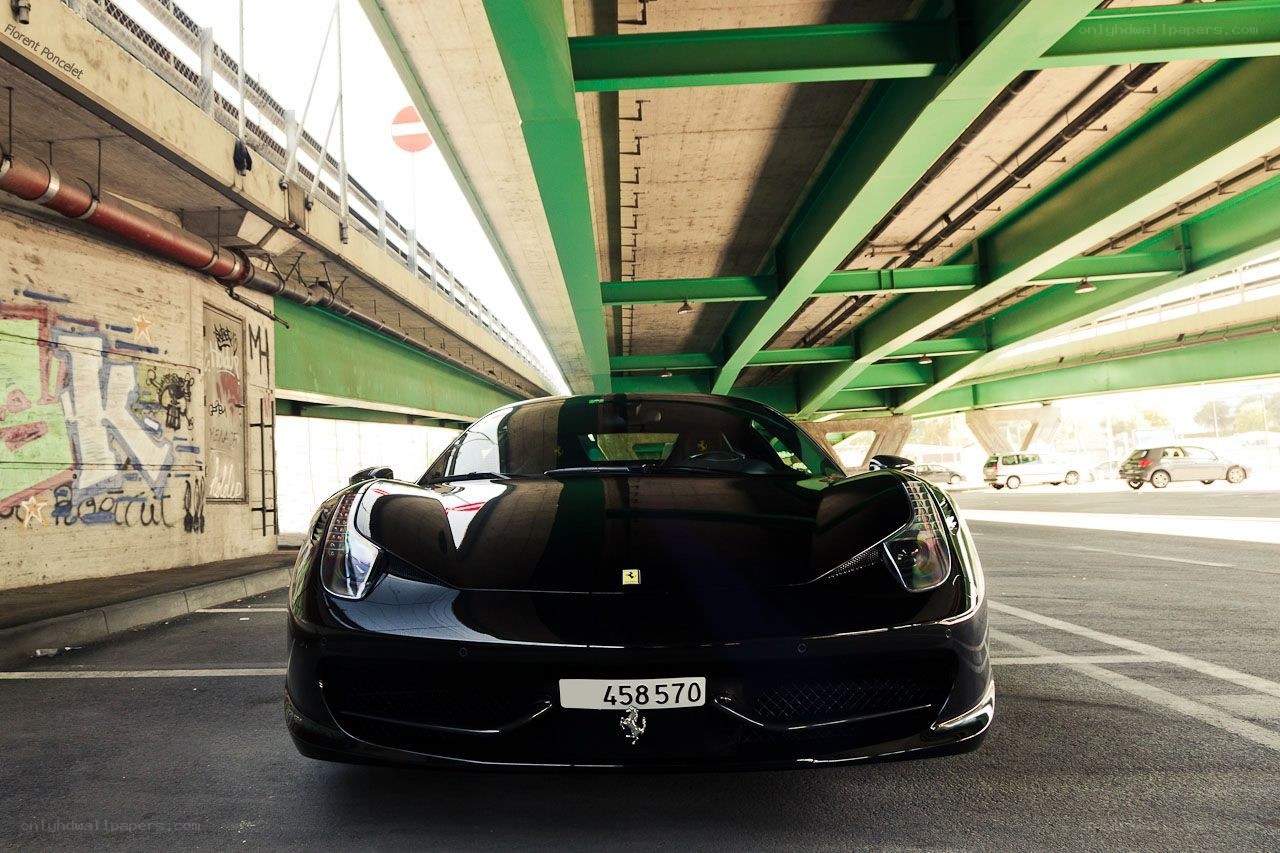 Black Ferrari under a green bridge