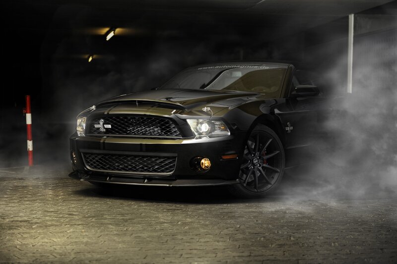 Black Ford Mustang in a smoky garage