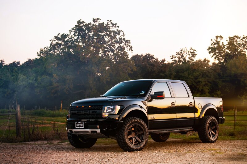 Black Ford Raptor truck in field