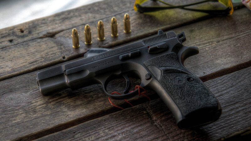 Black handgun with bullets on wood