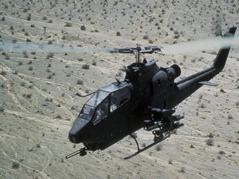 Black helicopter flying over desert