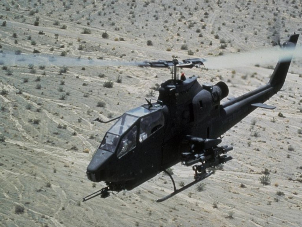 Black helicopter flying over desert