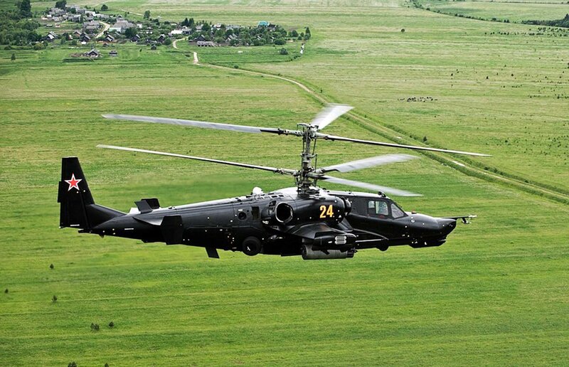 Black helicopter flying over fields