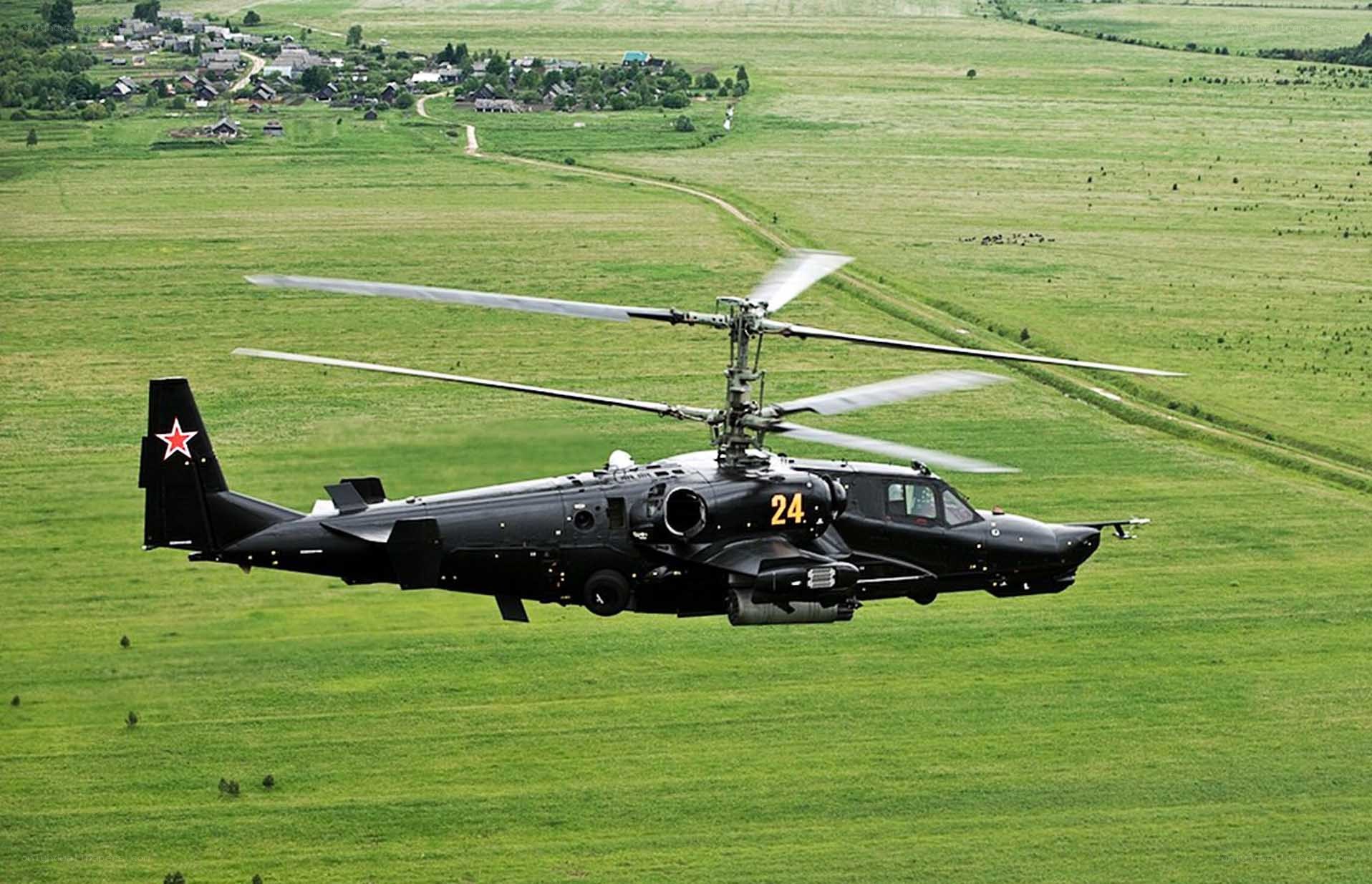 Black helicopter flying over fields
